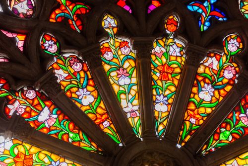 Free Colorful stained glass window with floral patterns in a cathedral setting. Stock Photo