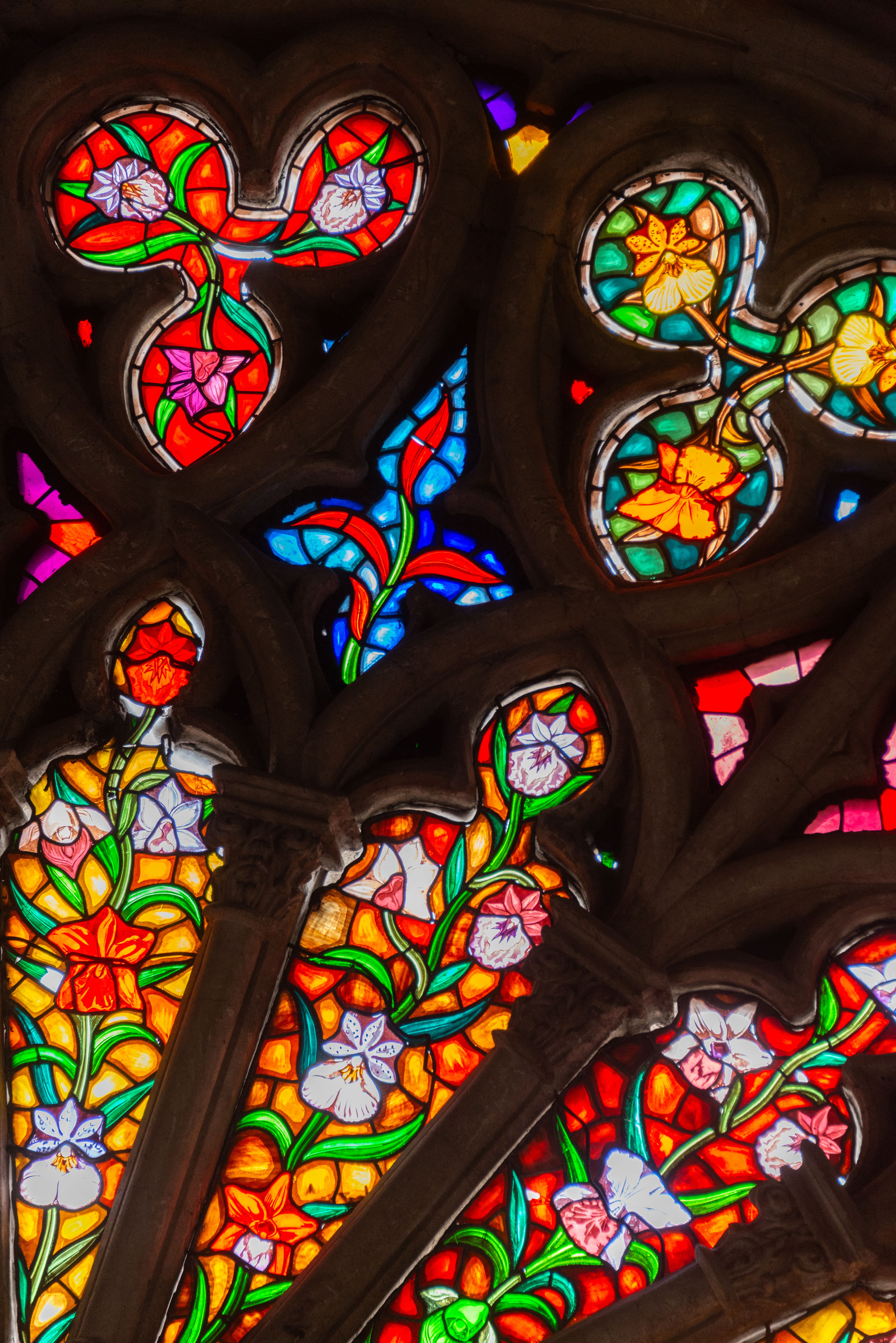 Colorful stained glass window showcasing intricate floral patterns and religious art.