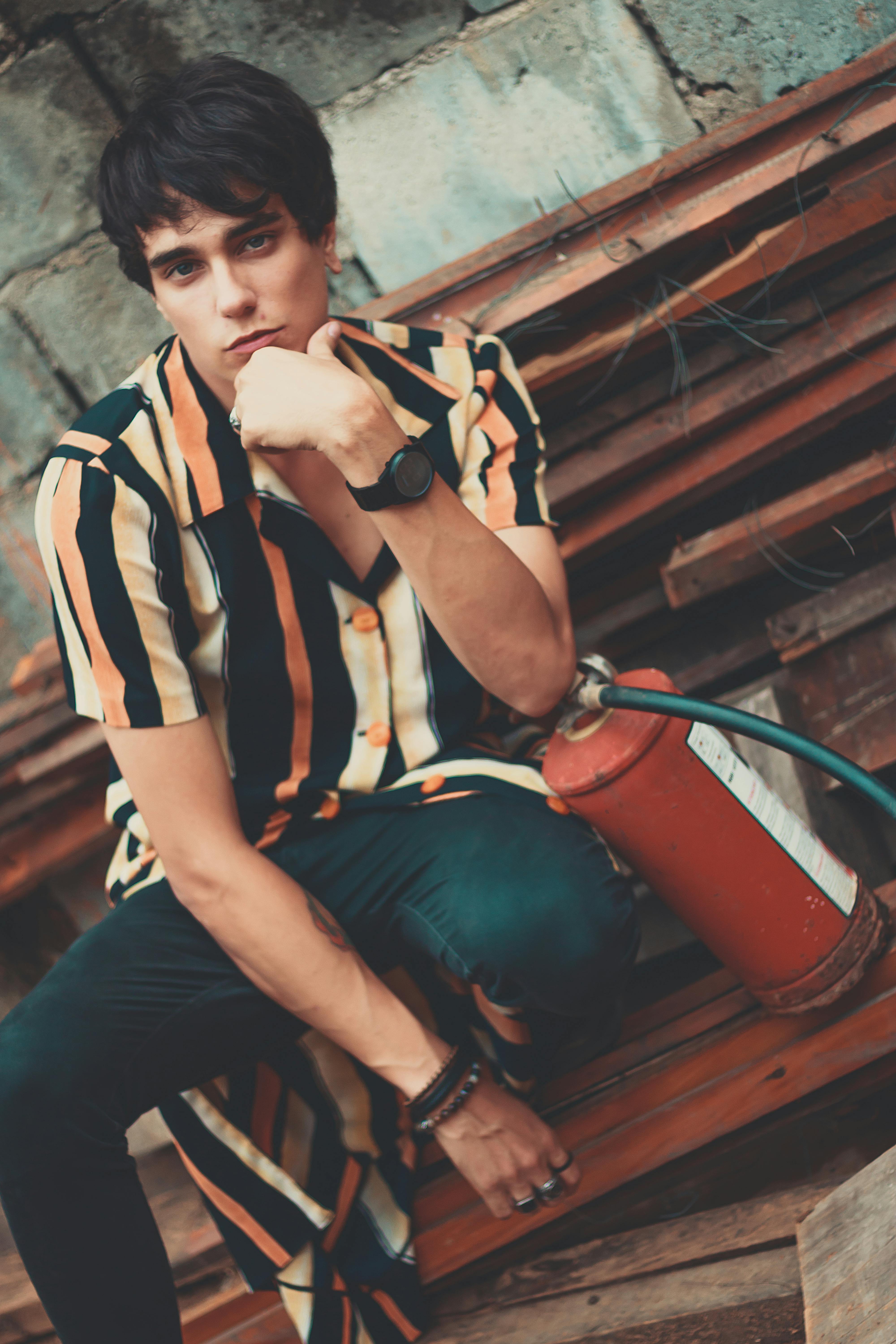 一名年轻人坐在城市户外，手持灭火器的肖像