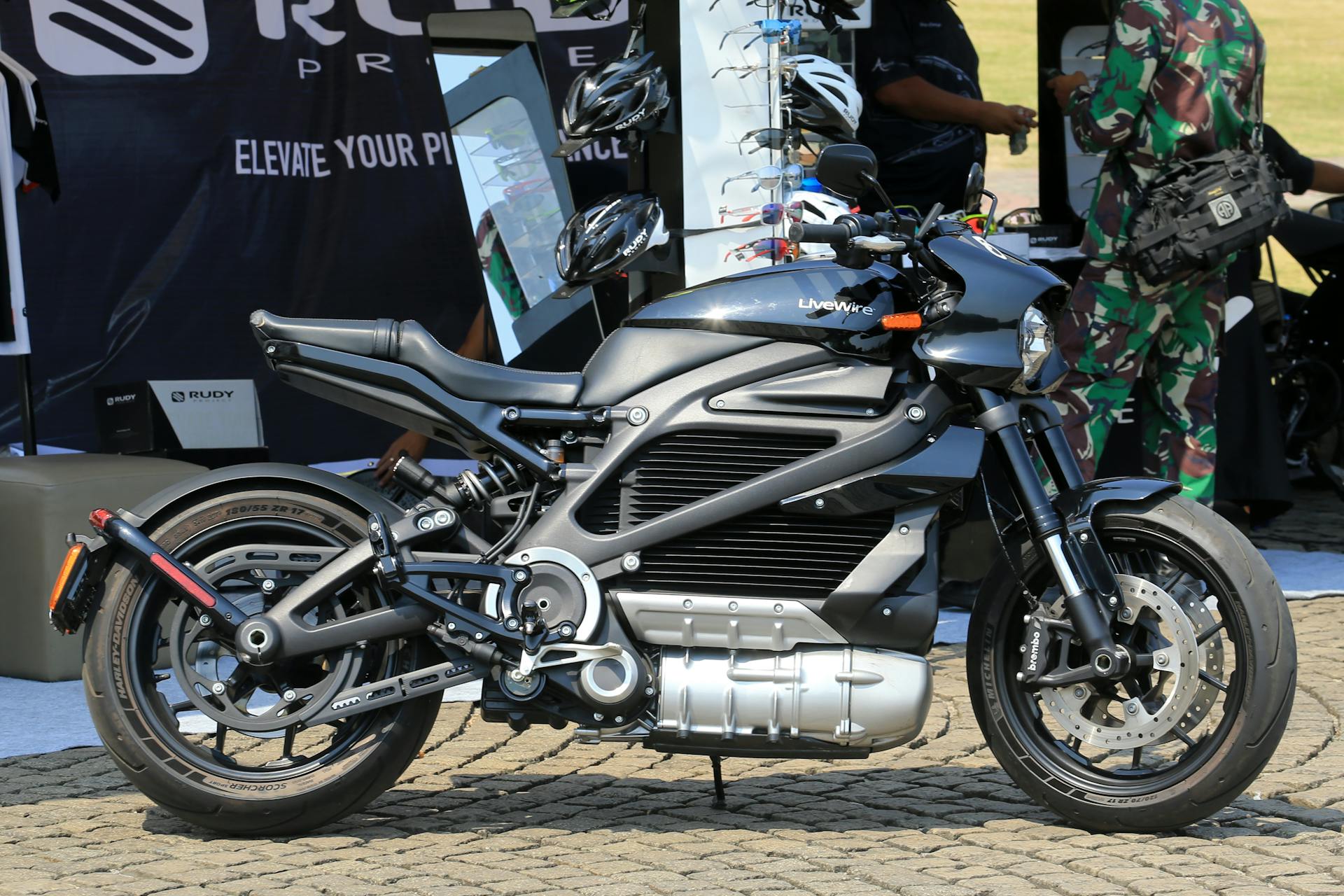 A modern black electric motorcycle displayed outdoors at a public event, showcasing futuristic design.