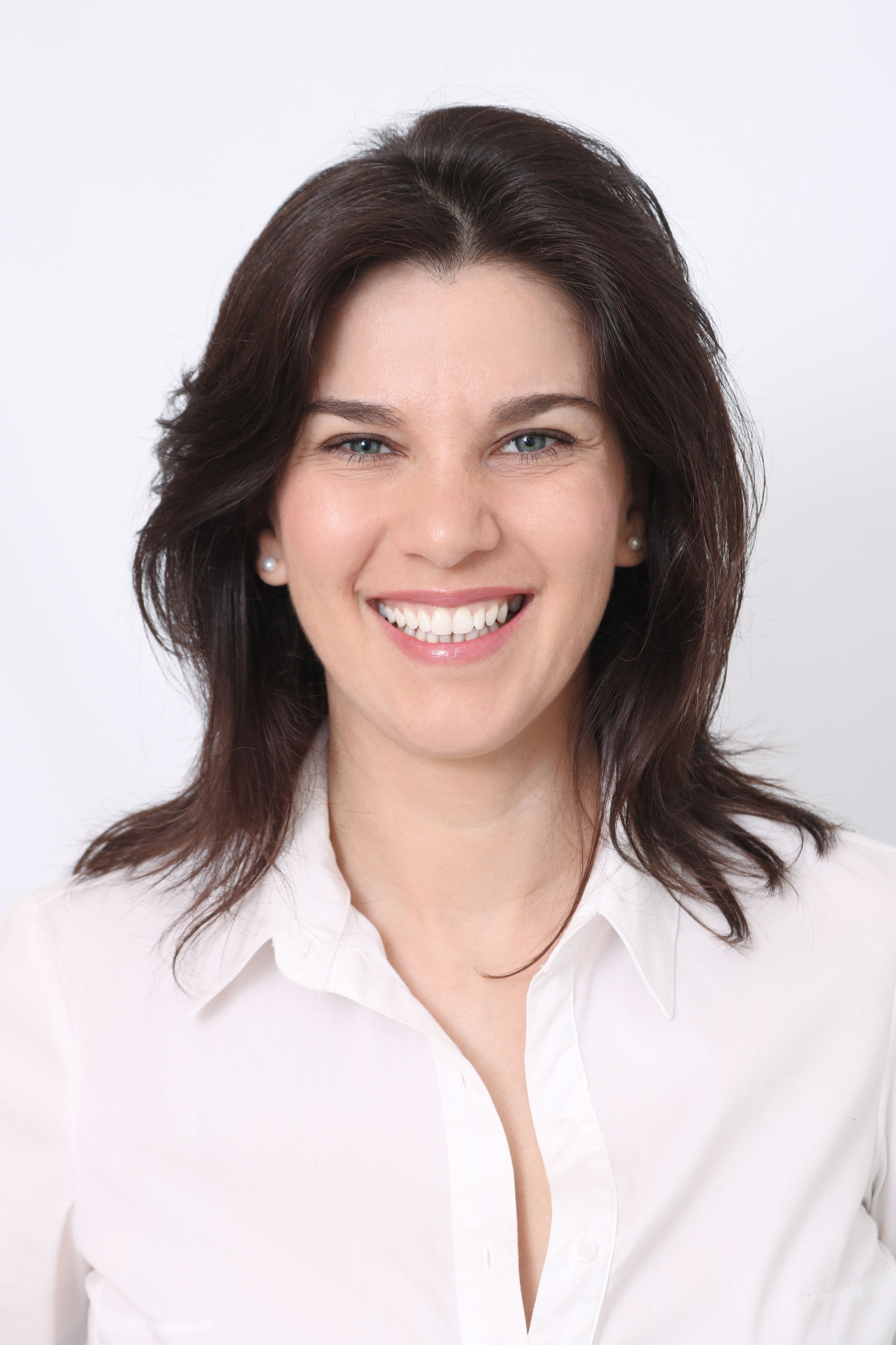Portrait of a woman with long black hair smiling against a white background.