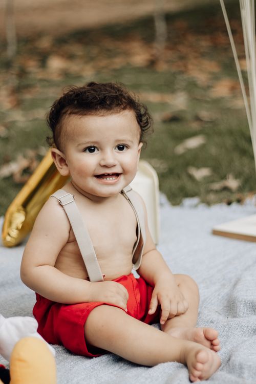 Free Smiling baby sitting on a blanket outdoors in São Paulo, Brazil, during a warm day. Stock Photo