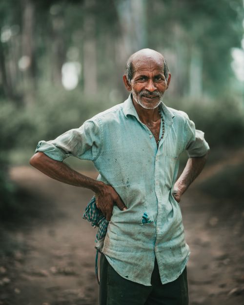 Free Elderly man stands confidently outdoors with hands on hips, wearing a shirt. Stock Photo
