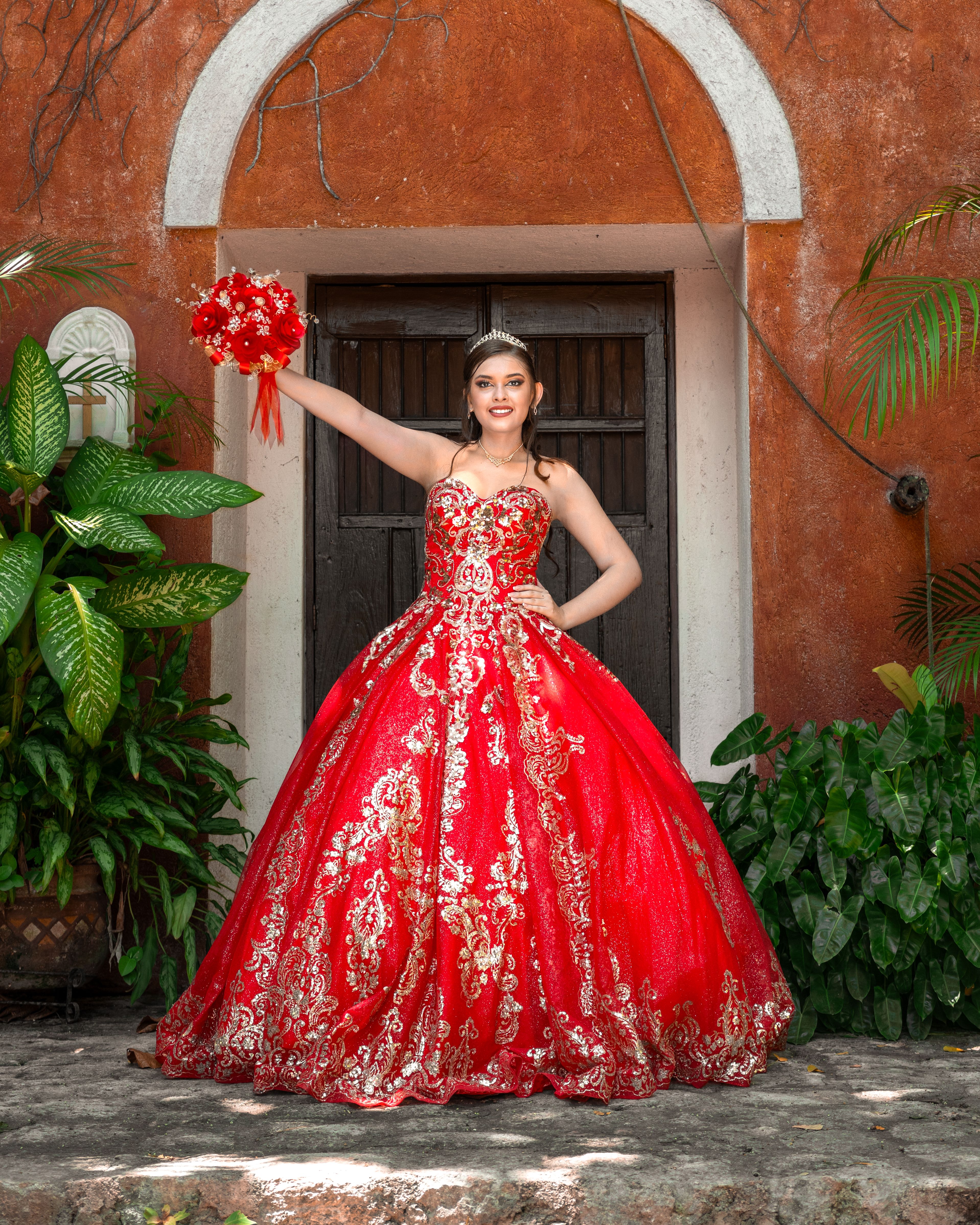 Young Woman in an Elegant Red Dress and Holding Flowers Standing Outside   Free Stock Photo