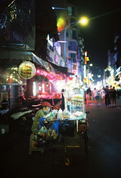 Bustling night street scene with a vendor cart in Ho Chi Minh City, Vietnam.