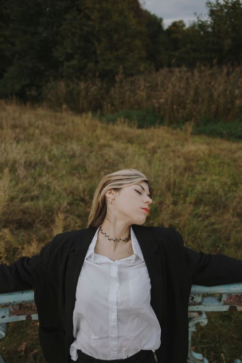 Free Woman in a blazer and white blouse relaxing outdoors in Berlin's countryside. Stock Photo