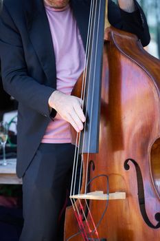 A musician passionately plays the double bass during an outdoor performance.
