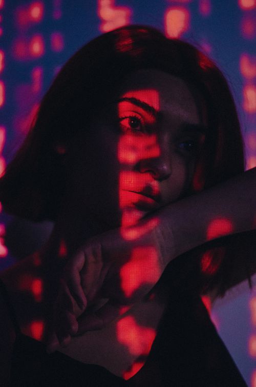 Free A woman illuminated by red light patterns, creating a dramatic and moody atmosphere. Stock Photo