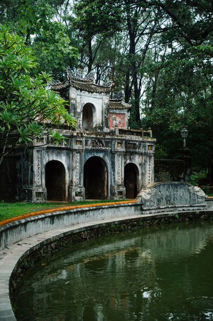 Scenic view of a traditional Vietnamese pagoda by a pond in Hue, nestled in vibrant greenery.