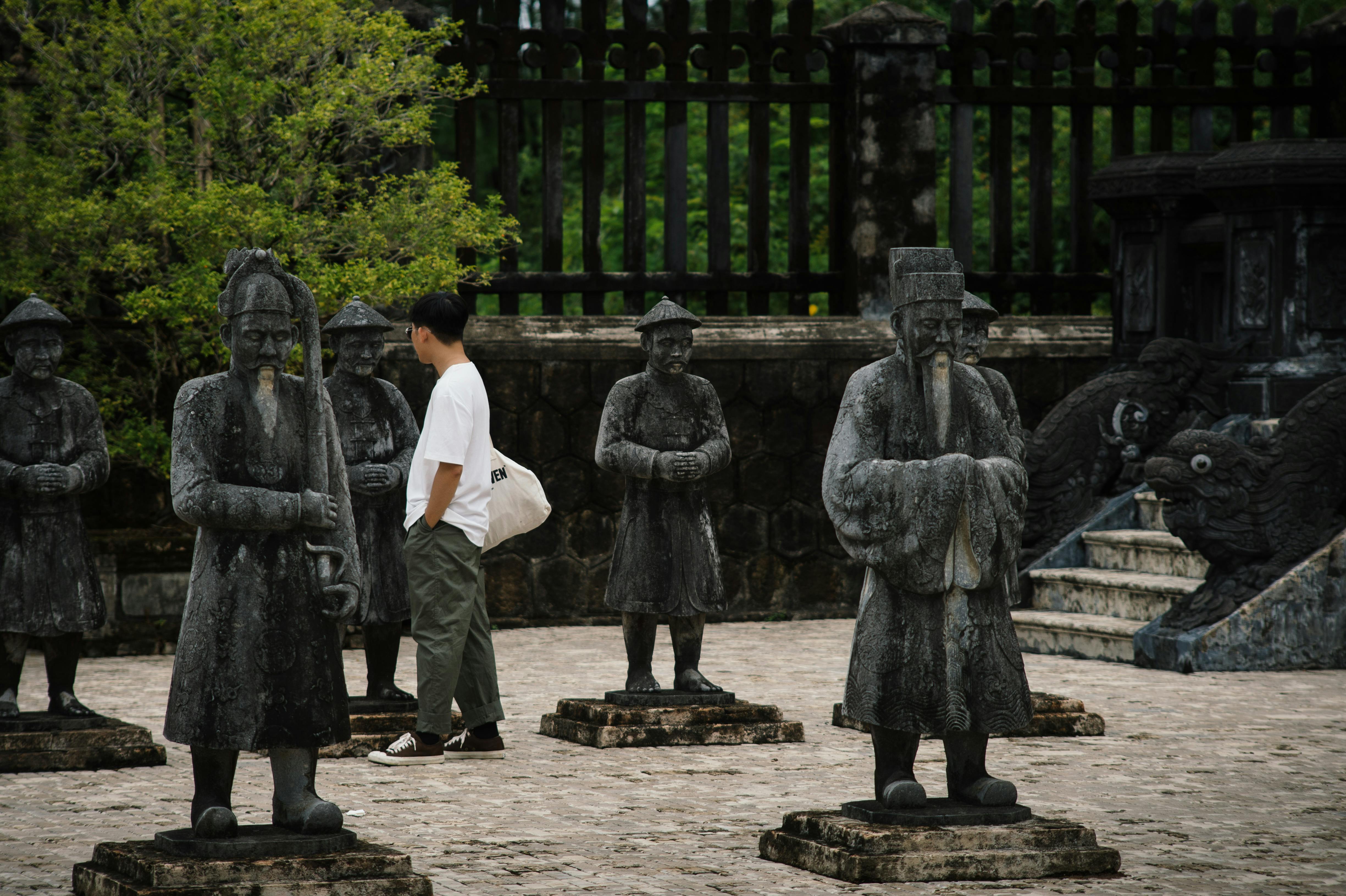 Tourist walking among sculptures at Khai Dinh Mausoleum in Vietnam, a UNESCO World Heritage Site.