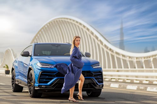 Model Posing in Front of a Blue Lamborghini Urus on a Bridge in Dubai