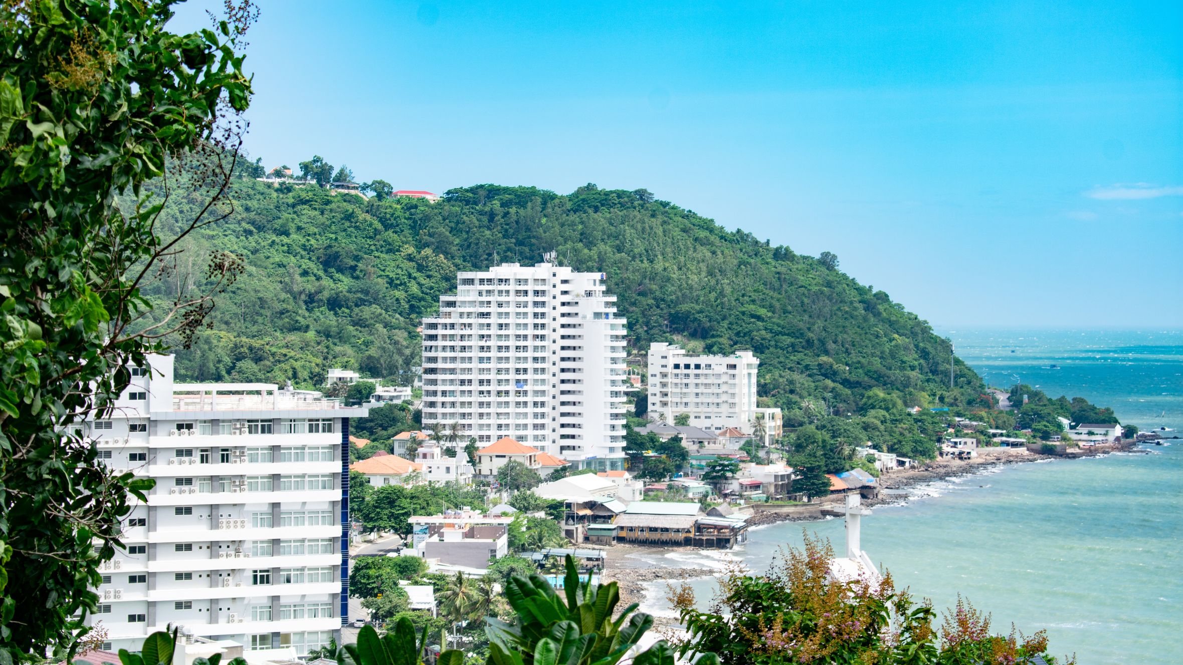 Scenic view of Vũng Tàu's coast with modern buildings and lush green hills.