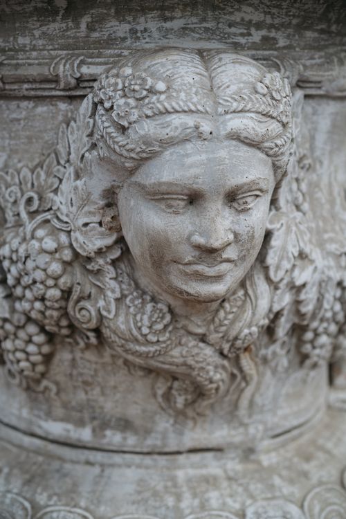 Free Close-up of an intricately carved stone sculpture depicting a human face with floral motifs. Stock Photo