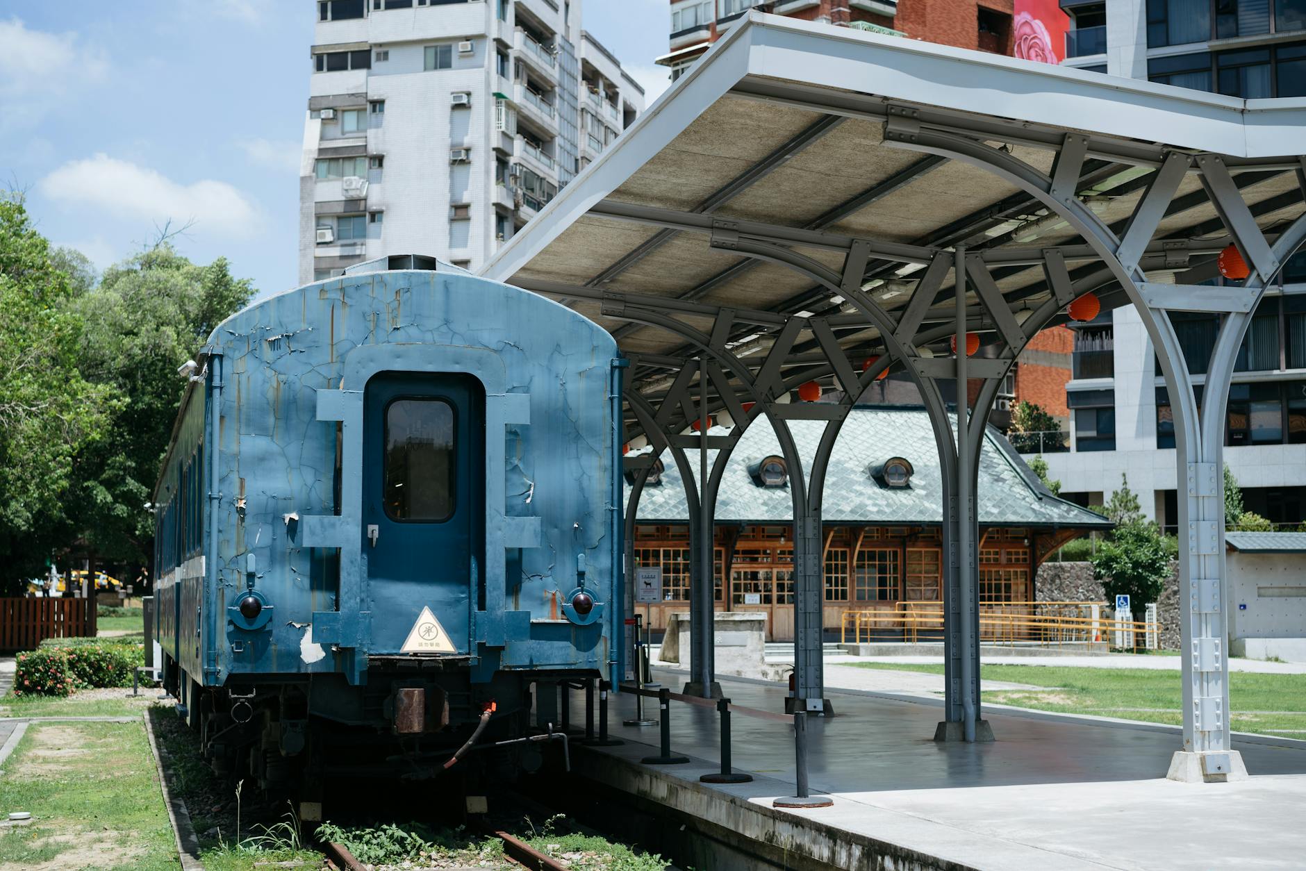 Vintage blue train at historic Taipei railway station platform under blue sky