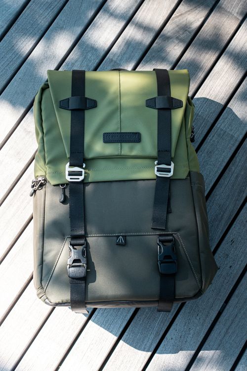Free Stylish olive green backpack resting on a sunlit wooden deck. Stock Photo