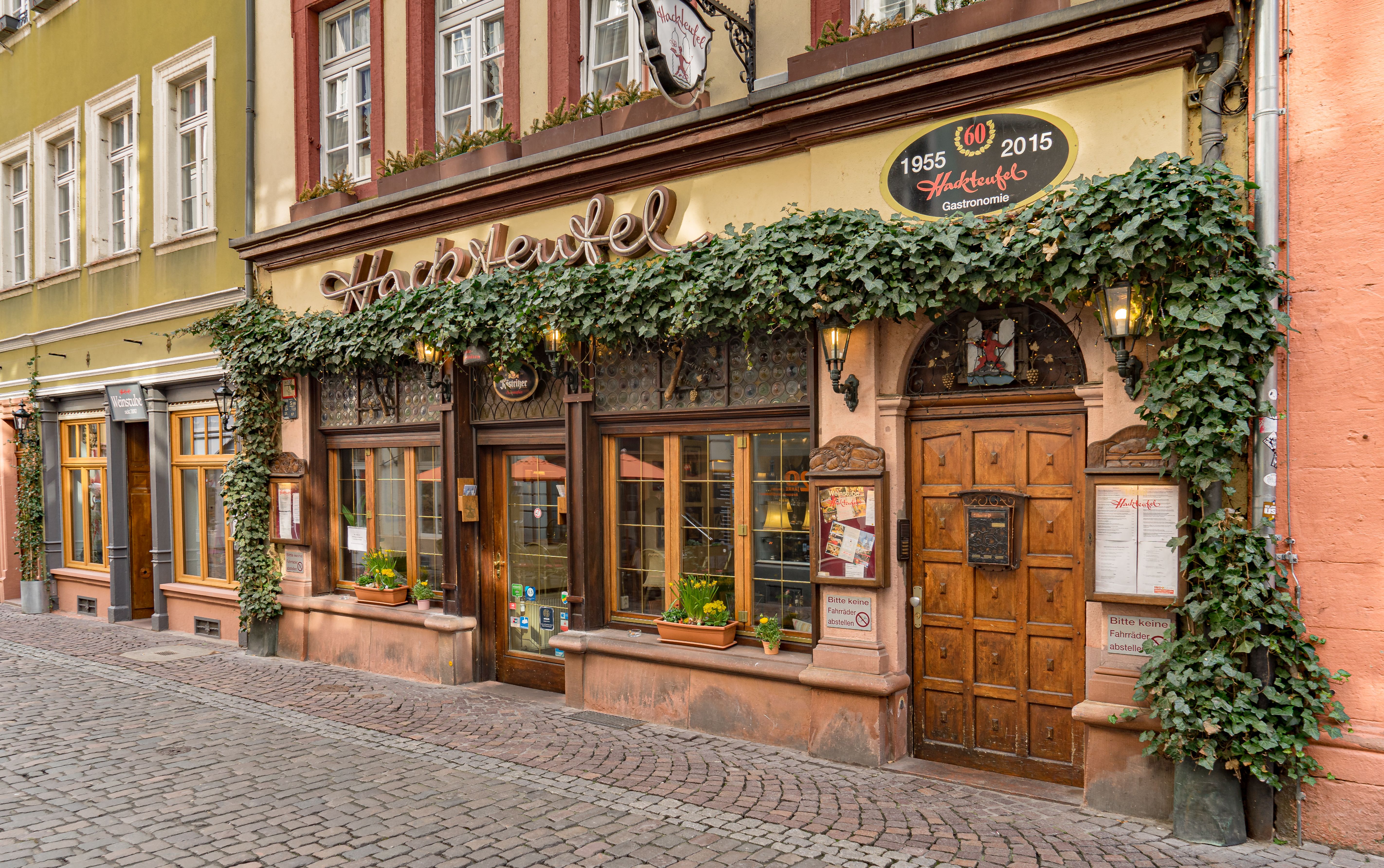 Historic restaurant exterior in Heidelberg's old town with ivy-covered facade and wooden door.