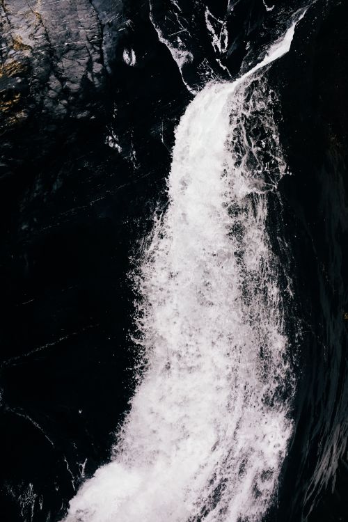 Free Dramatic waterfall cascading over dark rocks, showcasing nature's power and beauty. Stock Photo