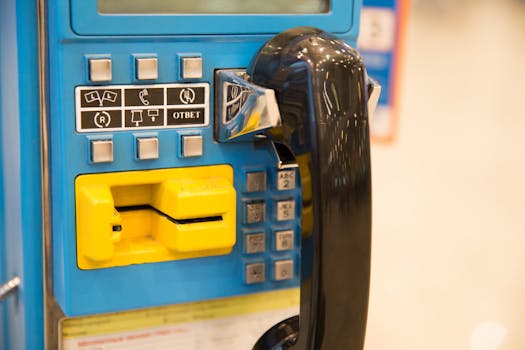 Close-up of a retro blue telephone booth with a black handset and coin slot.