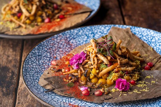 Vibrant Indian street food dish with edible flowers and spicy garnish on a decorative plate.