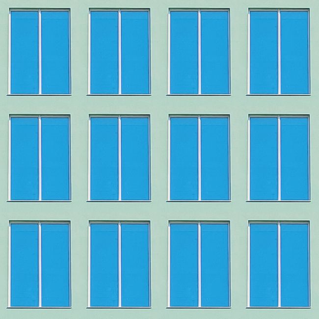 Minimalist facade with blue windows in Porto, Portugal, highlighting geometric urban design.
