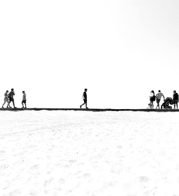 People walking on a beach boardwalk in Gafanha da Encarnação, Portugal.
