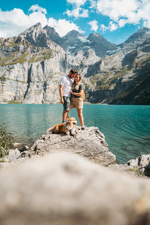 Free Couple of Tourists with a Dog at Oeschinen Lake in Switzerland Stock Photo