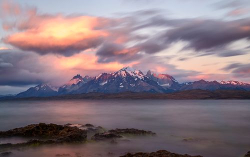Free Stunning view of mountains and pink clouds reflected on a serene lake during sunset. Stock Photo