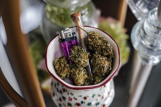 Aesthetic display of cannabis buds, lighter, and joint in a vintage bowl. Perfect for lifestyle themes.
