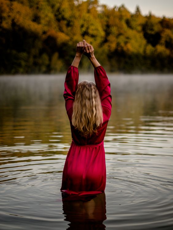 A woman in a red dress is standing in the water · Free Stock Photo