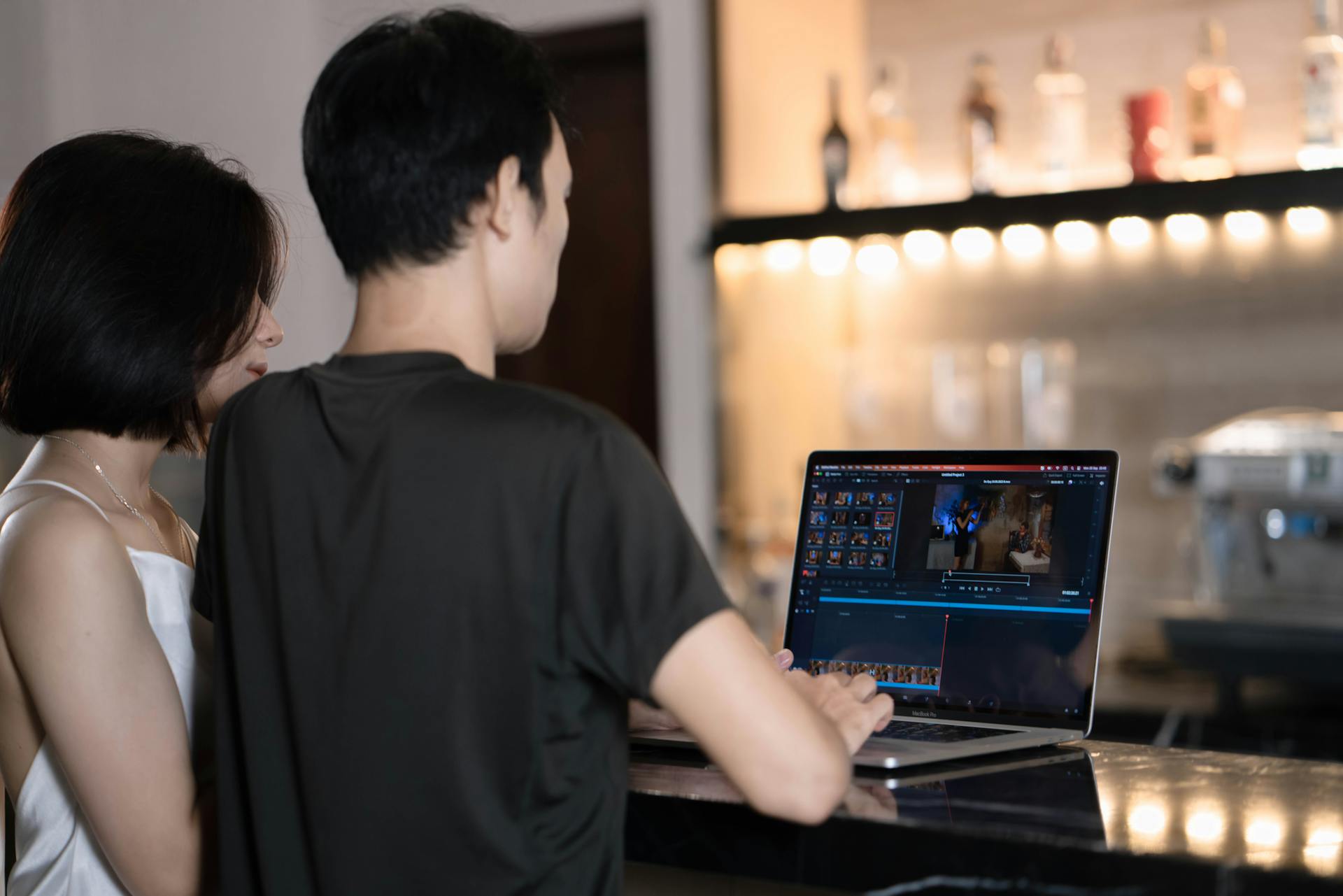 Two Asian professionals working together on a laptop in a modern café setting.