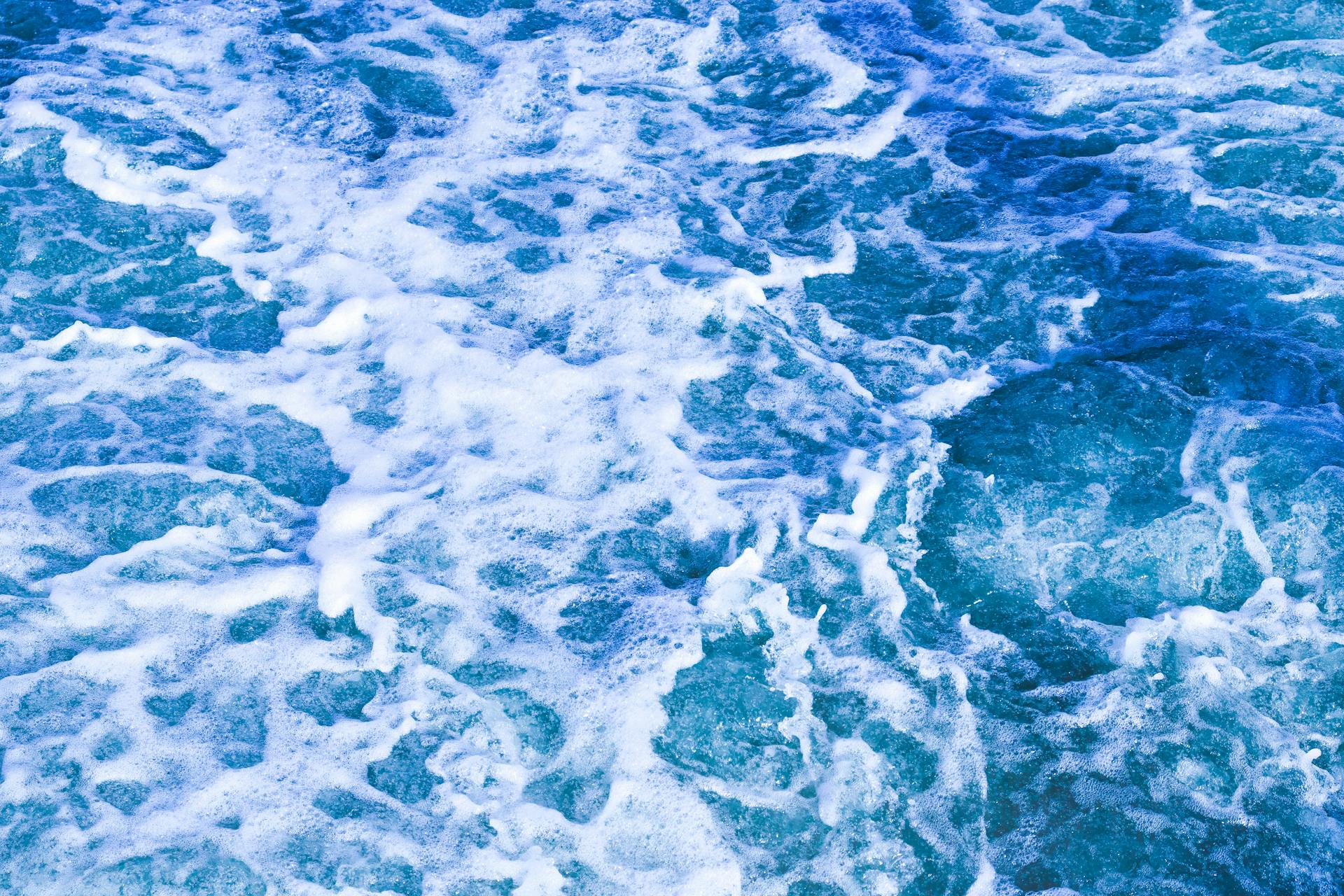 Vibrant blue ocean waves with frothy white foam creating a dynamic, textured seascape.