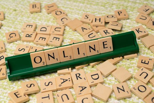 Free Scrabble tiles spelling 'online' on a green tray amidst scattered tiles, symbolizing digital connectivity and language. Stock Photo