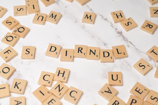 Scrabble tiles spell 'Dirndl' on a marble surface, showcasing cultural heritage.