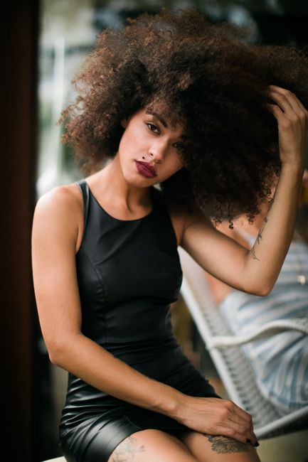 Elegant portrait of a woman with natural curly hair and stylish fashion in a modern setting.