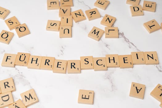 Scrabble tiles arranged to spell 'Führerschein' on a marble surface, representing language and word games.