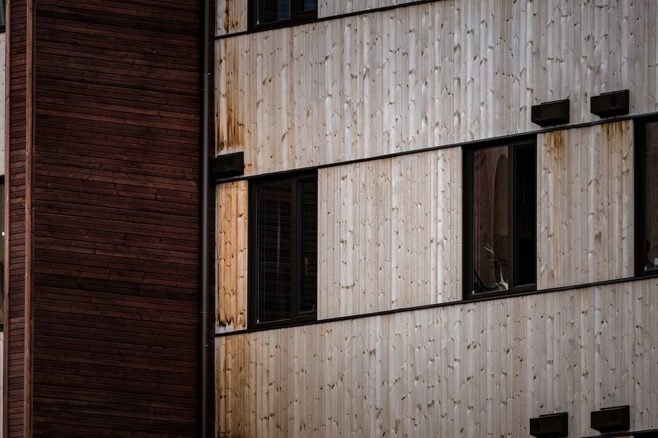 Close-up of a modern building facade with alternating wooden panels and windows.