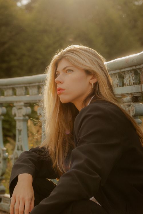 Free A thoughtful woman in a black suit basks in golden hour light outdoors. Stock Photo
