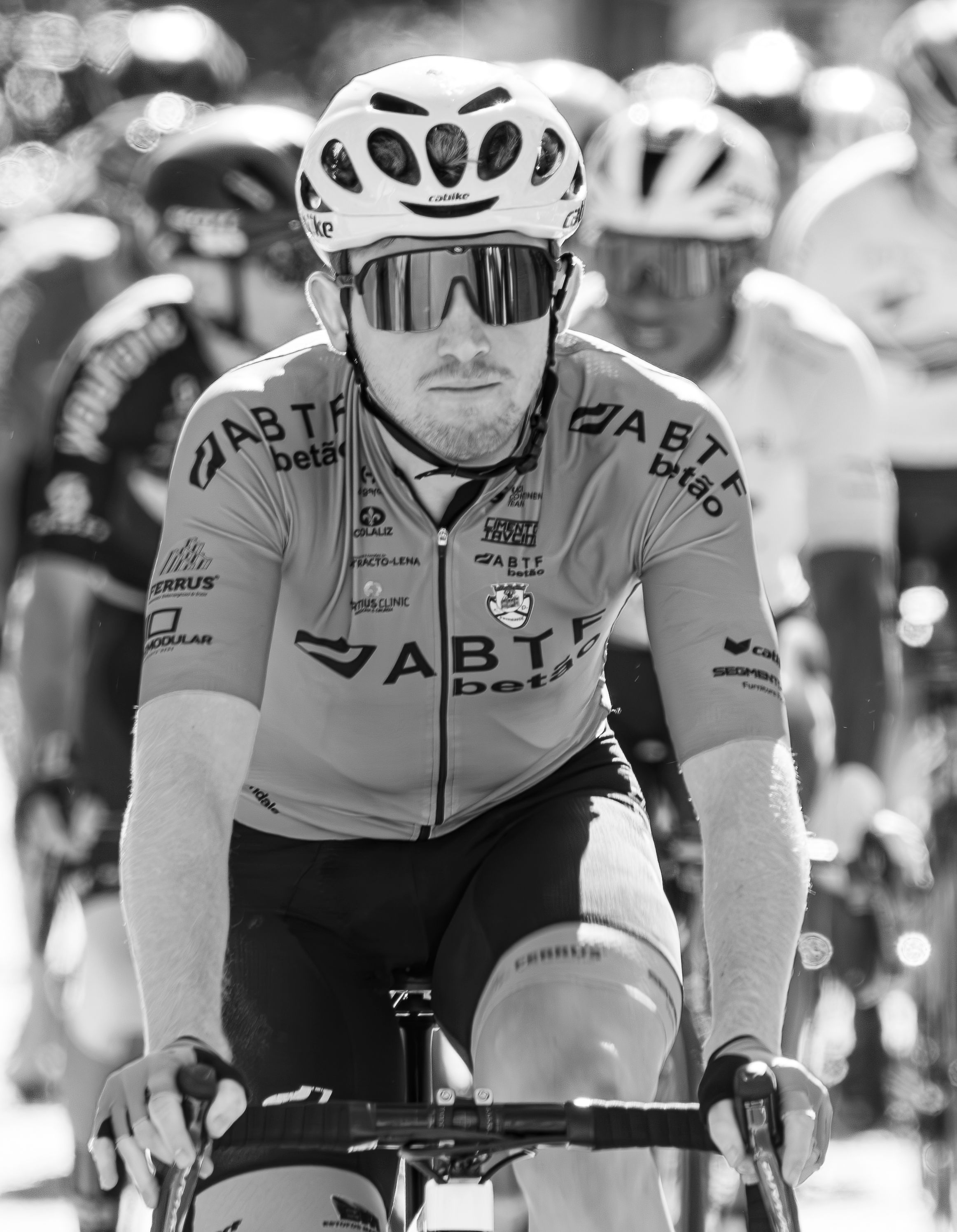 Focus on a cyclist wearing a helmet and sunglasses during a competitive race.