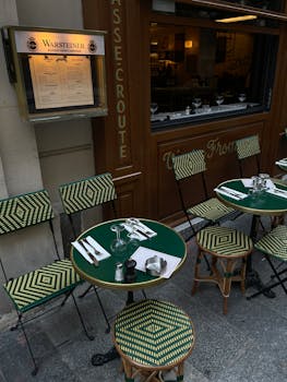 Charming city cafe with green chairs and tables, providing outdoor dining experience.
