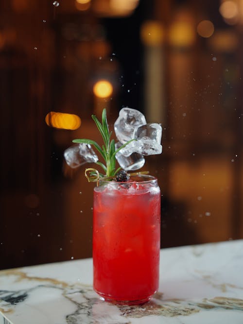 Ice Cubes Falling Down into Red Cocktail