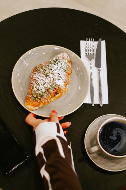 A freshly baked croissant with coffee on a black table, perfect for breakfast.