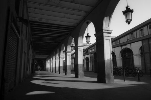 Free A dramatic black and white image of a colonnade with hanging lanterns and city streets. Stock Photo