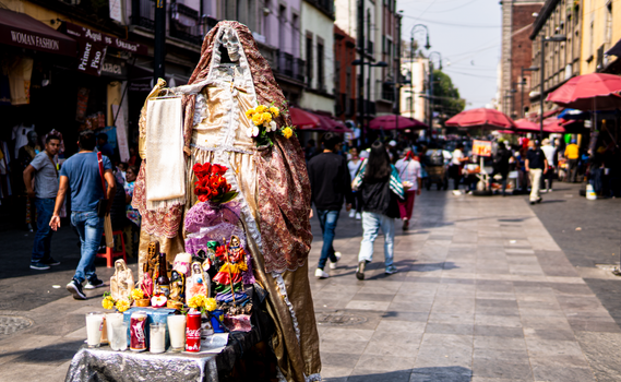 A vibrant Day of the Dead altar with colorful offerings in bustling Mexico City street.