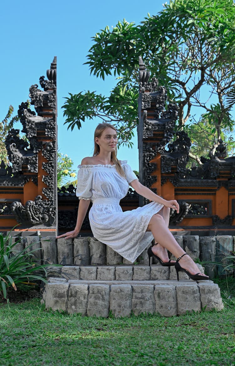 Blonde Woman In White Dress Sitting In Garden