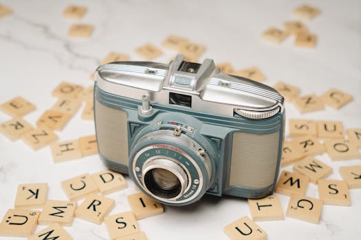 Retro camera surrounded by vintage letter tiles on a marble table, suggesting nostalgia.