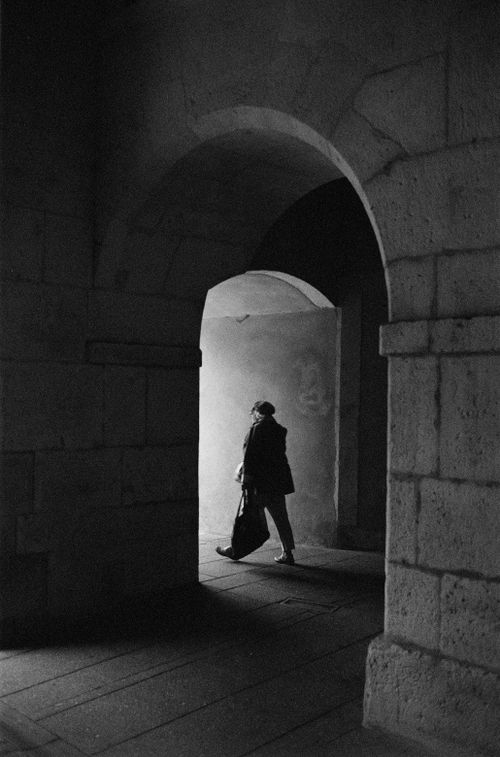 Free A lone figure walking through a historic archway in Nancy, France. Dark and moody. Stock Photo