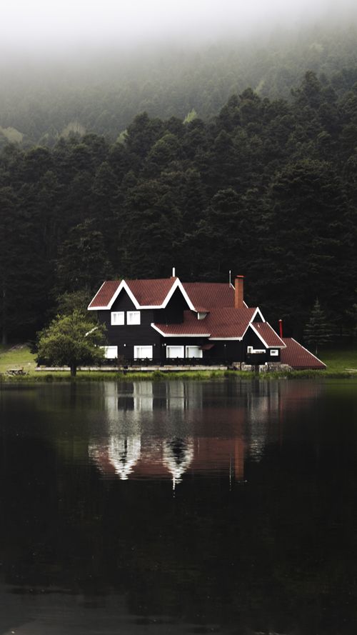 Free A serene black and white house reflecting in a foggy lakeside forest, creating a peaceful atmosphere. Stock Photo