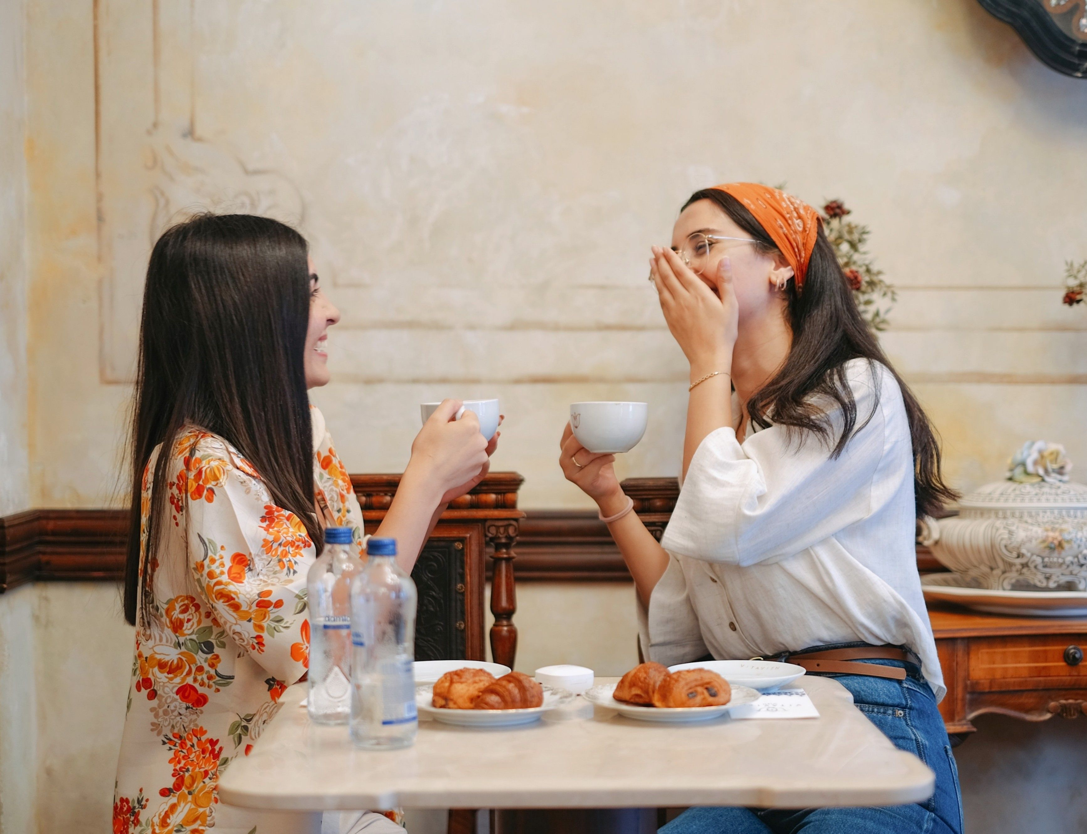Two women sharing happiness and coffee at a cozy cafe.