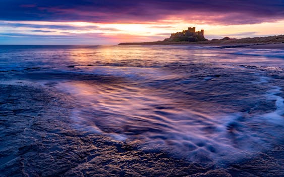 沿海城堡与海岸线上，日出色彩鲜艳，海浪宁静，景象十分壮观