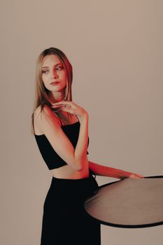Fashion portrait of a blonde woman posing confidently in a studio, showcasing modern style.